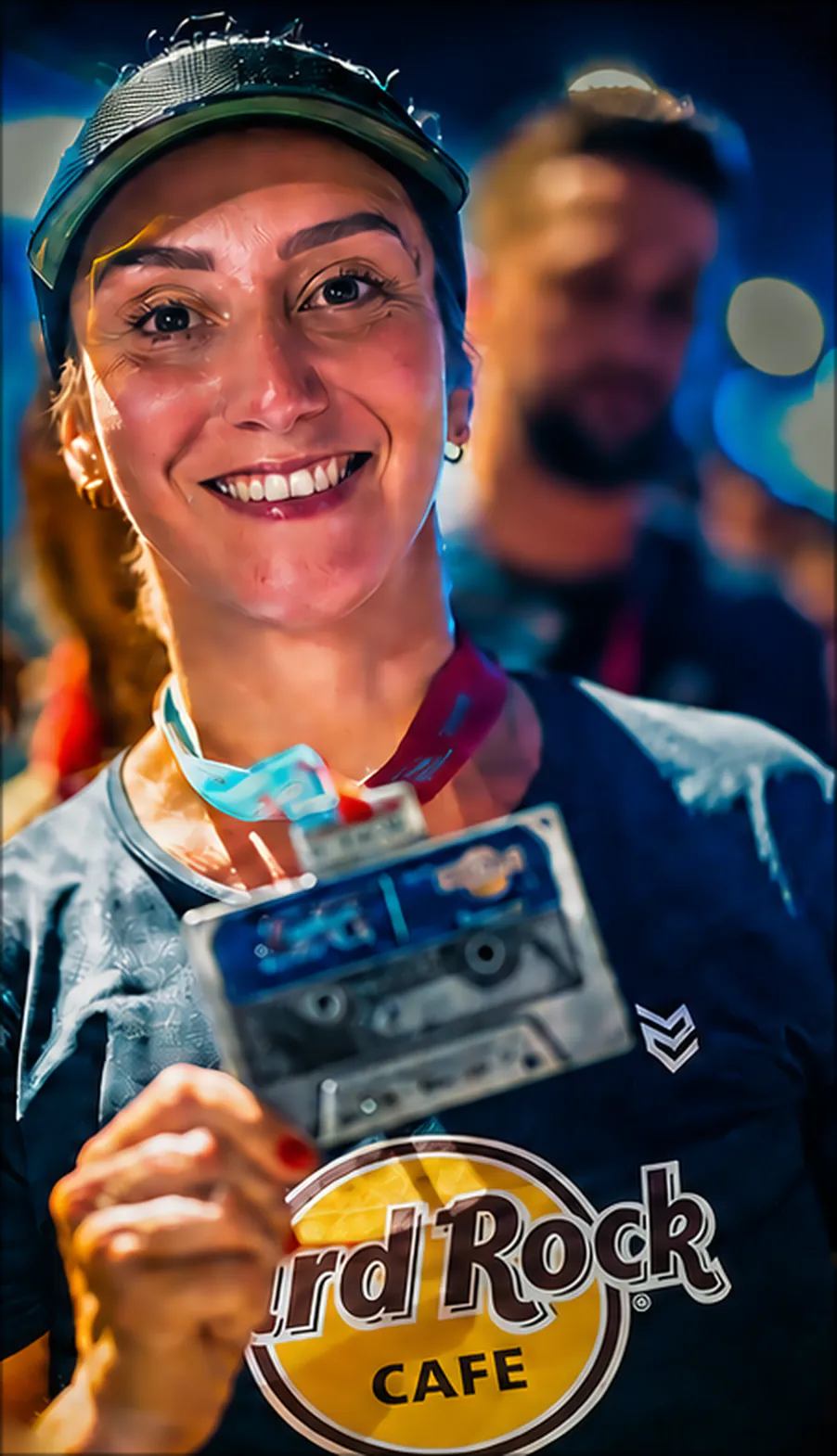 Atleta sorrindo e mostrando a medalha em forma de fita cassete