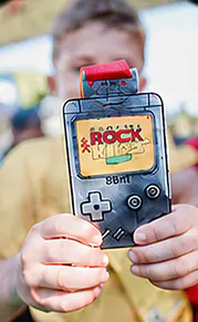 Criança mostrando a medalha em forma de videogame portátil