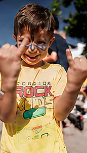 Menino com o rosto pintado fazendo o sinal do rock com as duas mãos