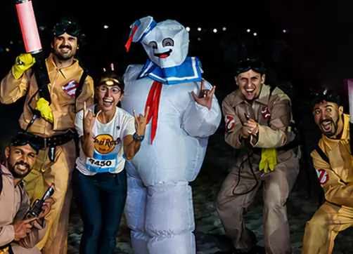 Equipe de caça-fantasmas com o boneco inflável de marinheiro e uma atleta, na areia